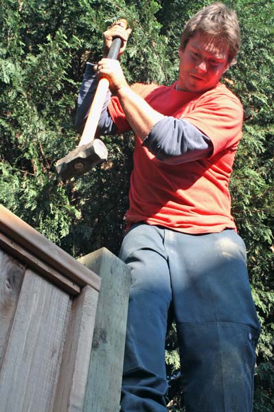 Adam Graham lends a hand to the carpenter by hammering the final section of fence into place. (Mitch Thompson photo)