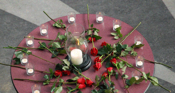 Fourteen roses and candles on a tabletop in the Richmond rotunda as a small gathering of students remembered. (Kim Ytsma photo)