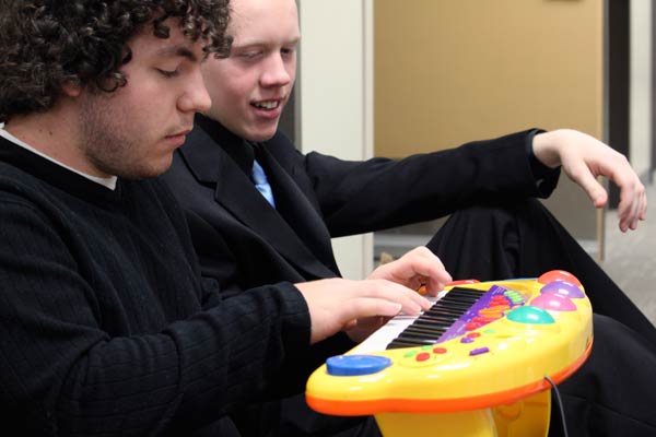 Alto sax student Laurence Cain, 18, watches guitar student Kyle Poehlke, 21, plays "A Thousand Miles" by Vanessa Carlton on a vintage Fisher Price toy piano. (Jacob Zinn photo)