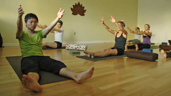 yoga class sitting on the floor, their hands in the air